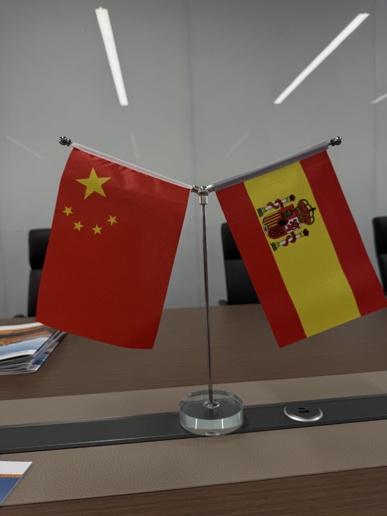 Banderas de China y España sobre la mesa de reunión en una fábrica durante la expedición comercial